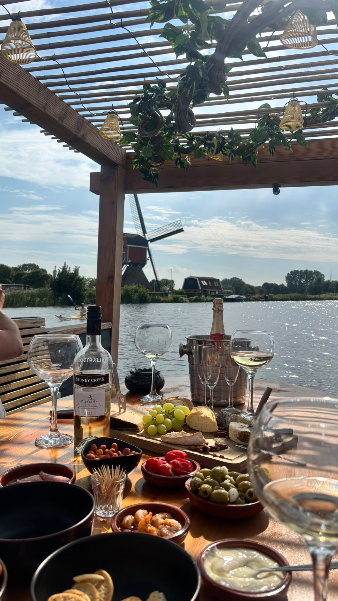 Borreltafel met hapjes, wijn en uitzicht op een Hollandse molen aan het water
