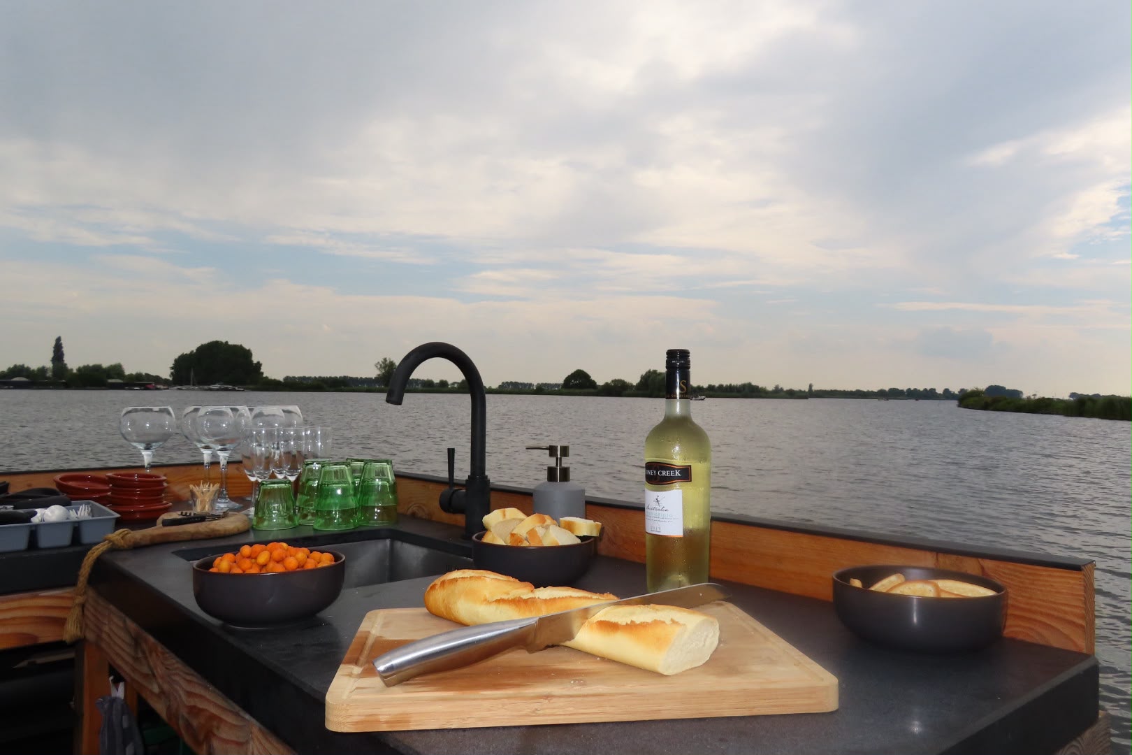 Buitenkeuken met spoelbak, brood, glazen en wijn aan boord