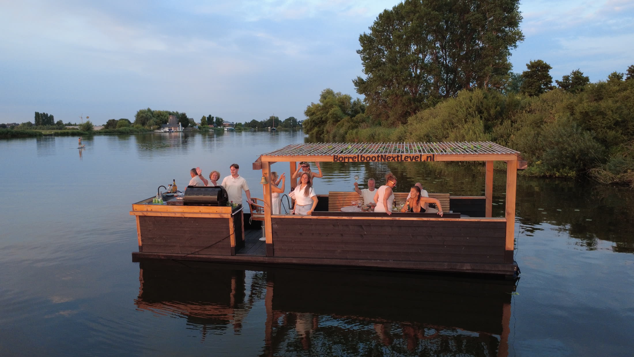 Luchtfoto van Borrelboot Nextlevel in de avondzon met zwaaiende gasten aan boord