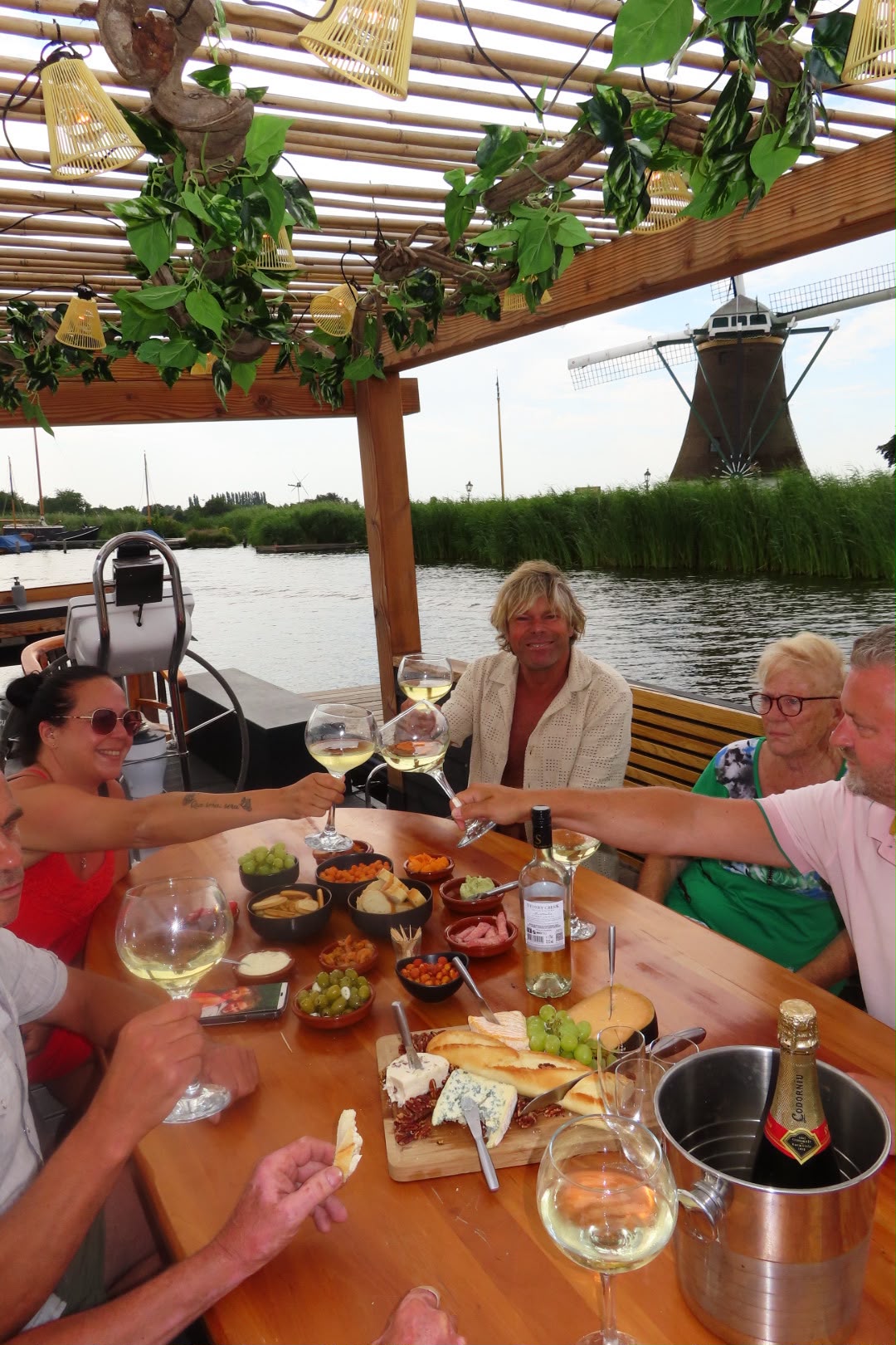 Gasten proosten aan boord met een molen op de achtergrond