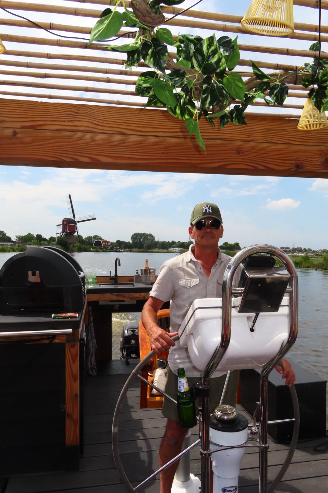 De schipper bij het stuurwiel met een molen op de achtergrond